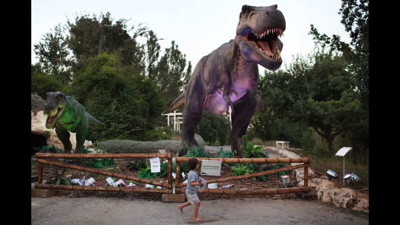 A child walks past a replica of a Tyrannosaurus rex during a visit to the Jerusalem Botanical Gardens on Monday, July 27.
