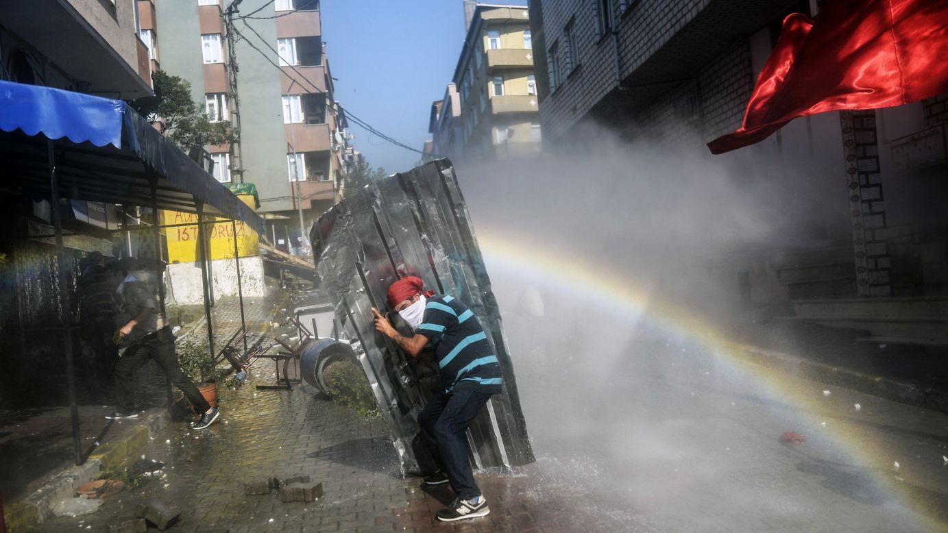 A left-wing militant shields himself from water cannons during clashes with Turkish police officers in Istanbul on Sunday, July 26. 
