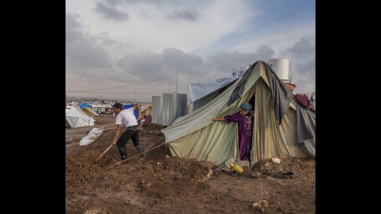 A Syrian refugee digs ditches around his family's tent in the Domiz camp in Iraq.