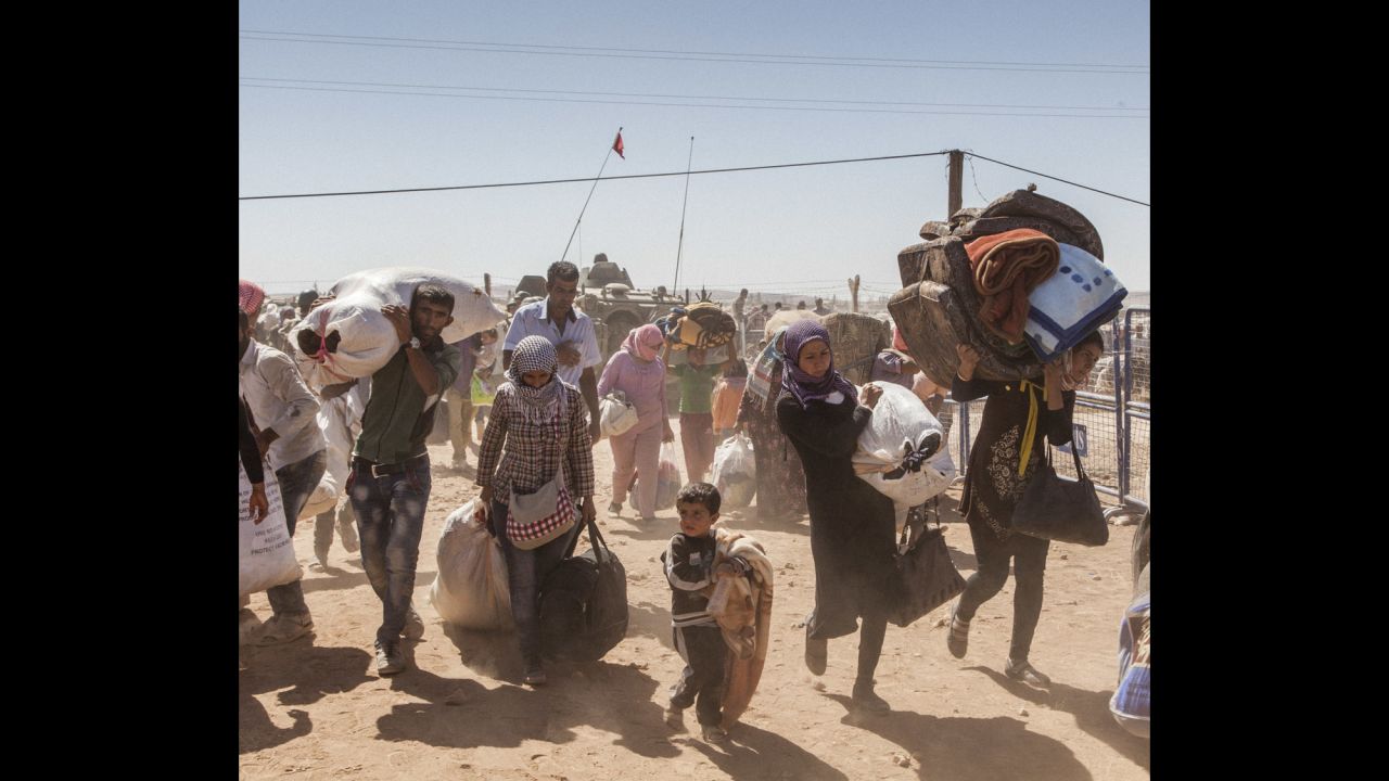 Syrian refugees cross the border into Turkey after fleeing fighting between Kurdish forces and the ISIS militant group.