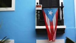  A for sale sign is seen hanging from a balcony next to a Puerto Rican flag in Old San Juan as the island's residents deal with the government's $72 billion debt on July 1, 2015 in San Juan, Puerto Rico. 