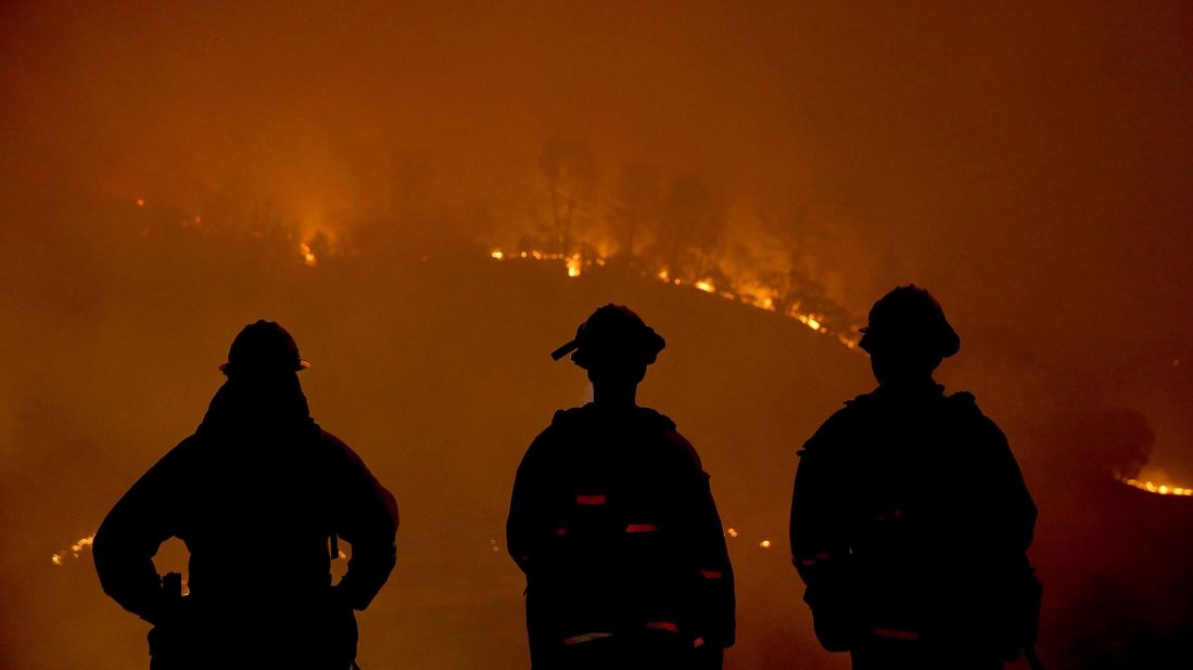 Firefighters look on as the Rocky Fire burns through trees on Sunday, August 2. 