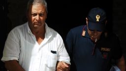 An Italian police officer walks with one of the suspects in Palermo.