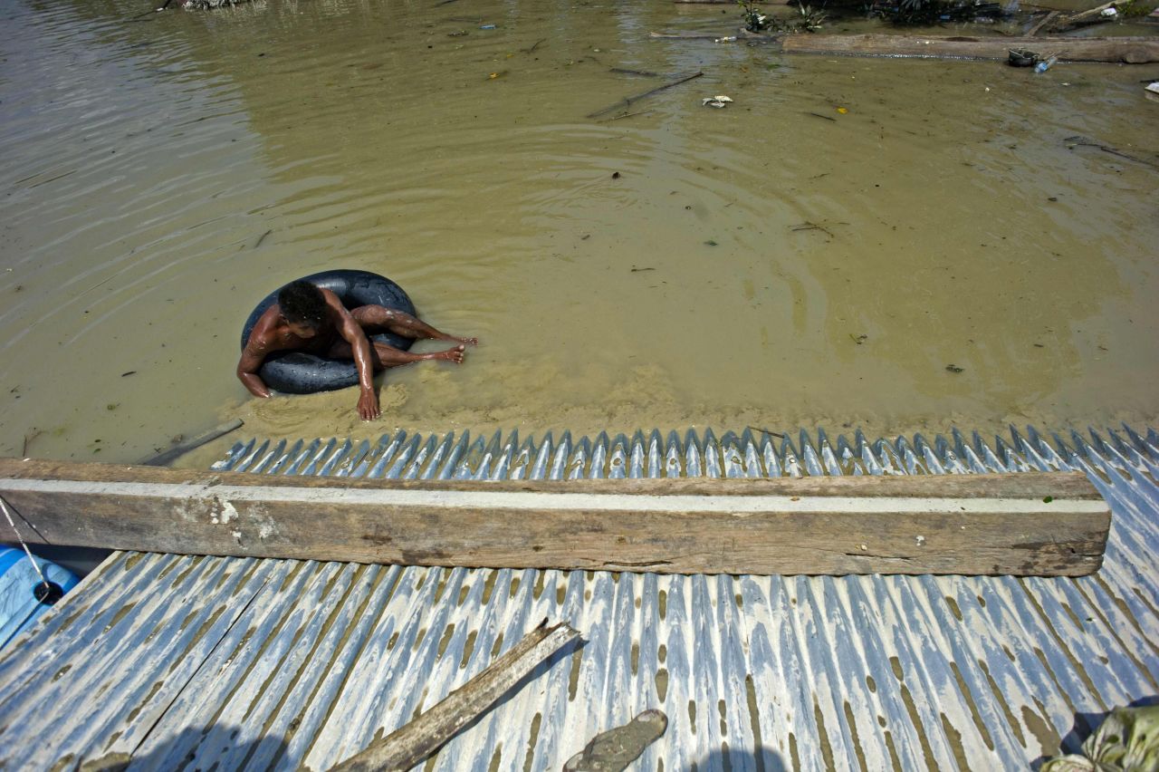 A man climbs to safety on a roof, escaping the flooding in Kalay, Myanmar on August 3.