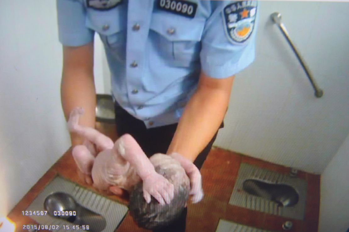 An image supplied by Beijing Tianqiao Police shows an officer holding the baby at the toilet on August 2, 2015.