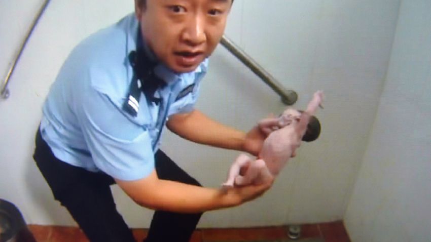 Handout image shows a frame grab of a Beijing Tianqiao Police video taken on August 2, 2015 of a Chinese policeman holding an abandoned newborn baby in a public toilet in Beijing. A newborn baby girl was abandoned in a public toilet and fell head-first down the pipe, reports said August 3, after her mother apparently gave birth in the facility.
