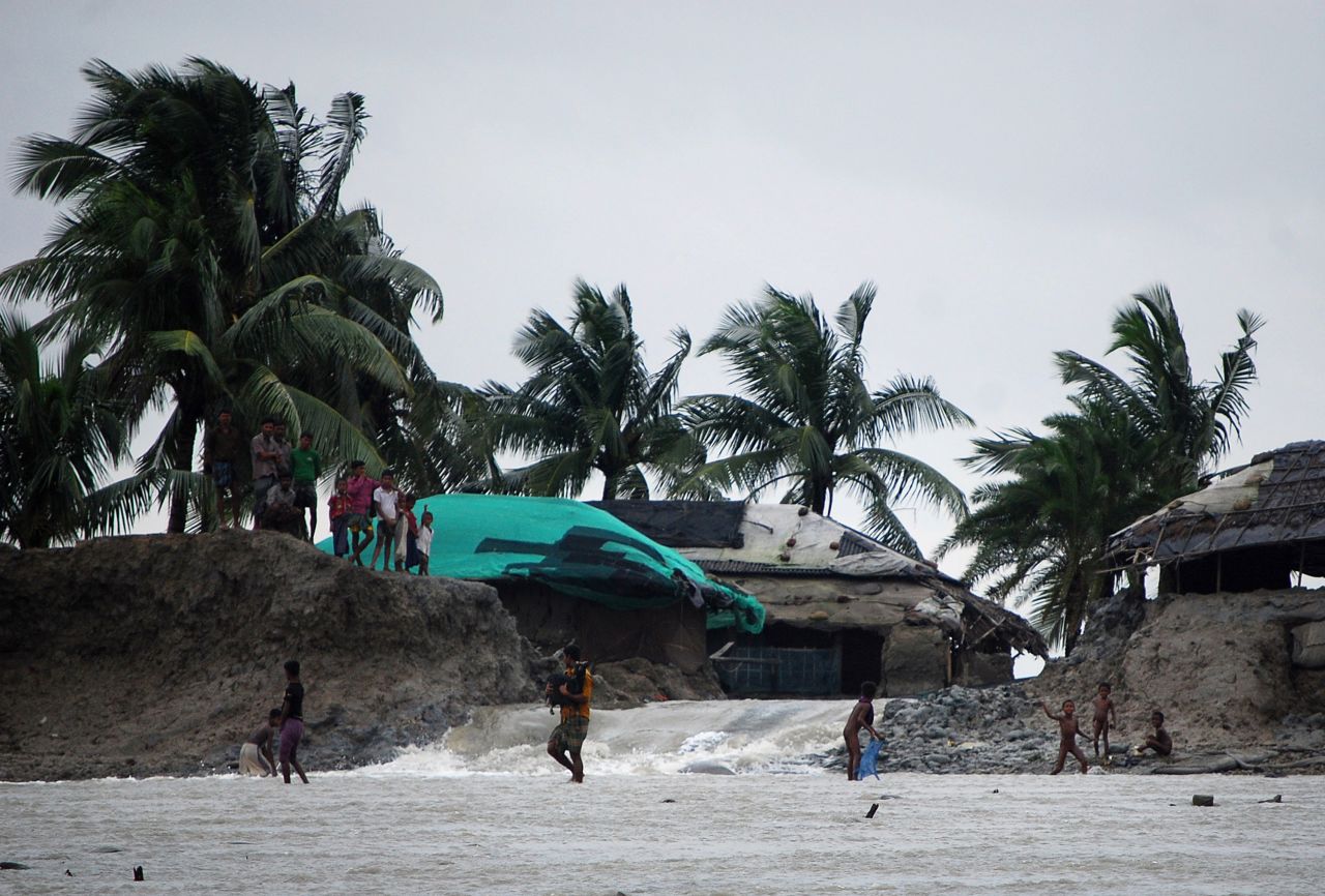 Bangladeshi villagers wade through flood waters in Cox's Bazar.