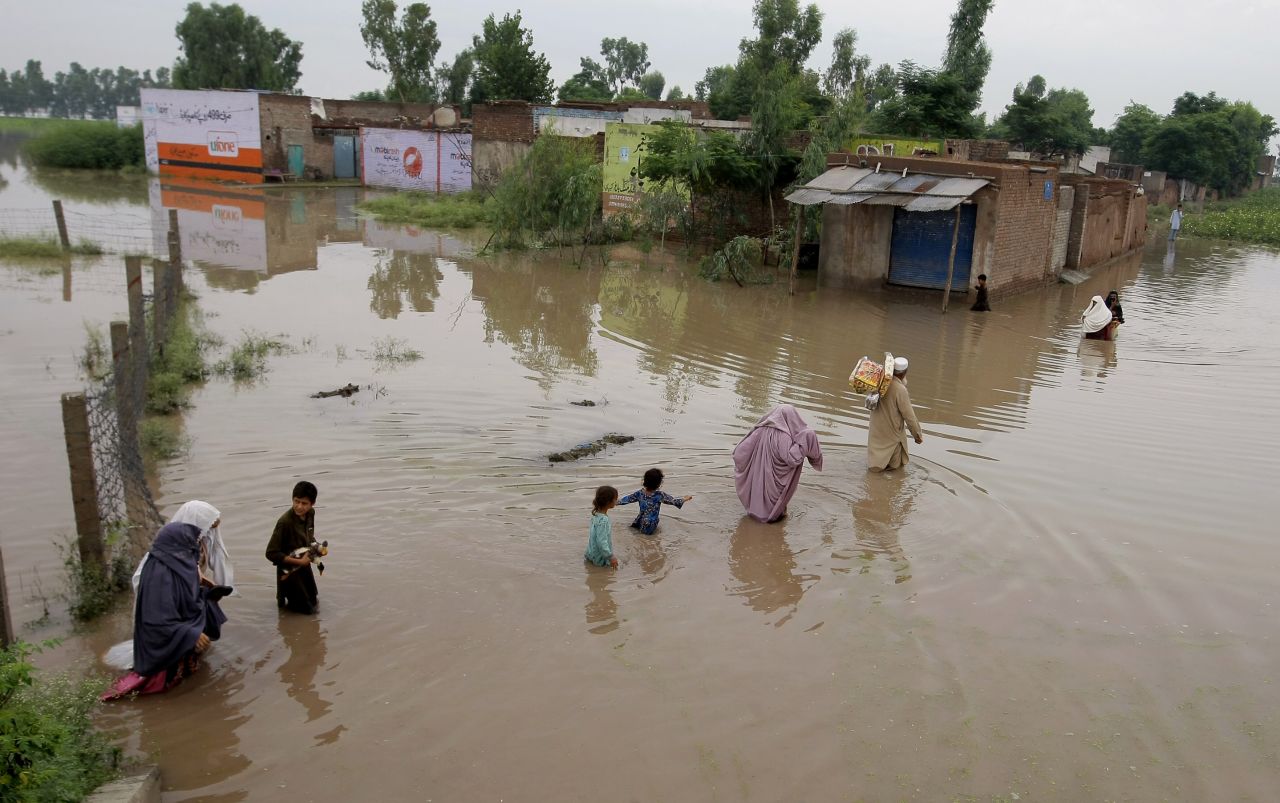 Pakistani villagers wade through floodwaters caused by heavy rains at a village on the outskirts of Nowshera near Peshawar, Pakistan, Sunday, Aug. 2, 2015. Flooding has left millions displaced throughout the region.