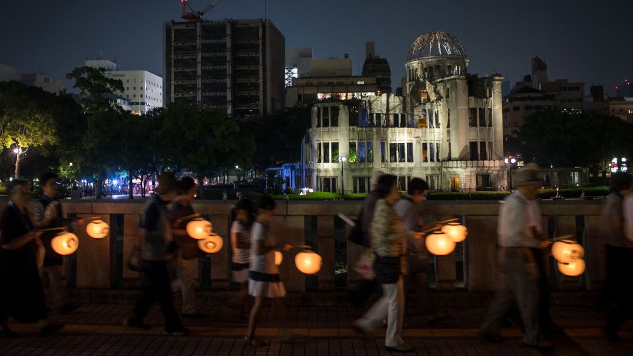 People carry lanterns past the memorial on August 5.