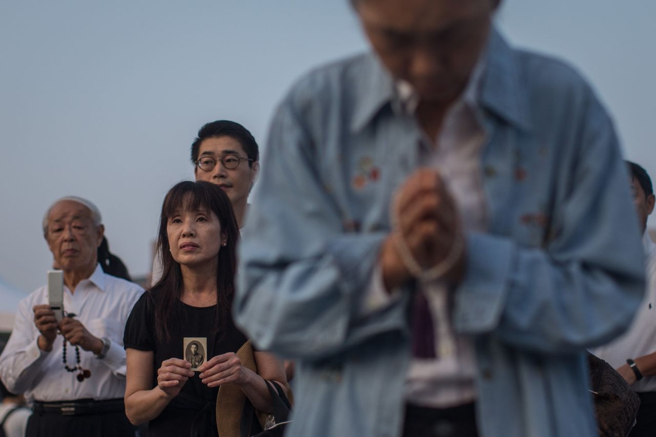 A woman holds a photograph as she prays at the Hiroshima Peace Memorial on August 6.