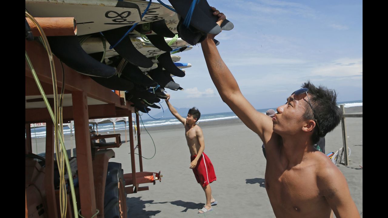 Surfers remove surf boards from a beach in Yilan County, Taiwan, Thursday, August 6.