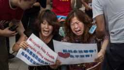 BEIJING, CHINA - AUGUST 07: Chinese relatives of passengers missing on Malaysian Airlines flight MH370 cry as they kneel in front of the media outside the Malaysian Embassy during a protest by relatives on August 7, 2015 in Beijing, China. France expanded its search for debris off Reunion Island Friday a day after Malaysia's prime minister announced that a piece of wing discovered last week is from Malaysia Airlines Flight MH 370 which vanished last year. Officials and experts from other countries including the United States and Australia have been more cautious, saying that more investigating needs to be done. (Photo by Kevin Frayer/Getty Images)