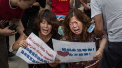 BEIJING, CHINA - AUGUST 07: Chinese relatives of passengers missing on Malaysian Airlines flight MH370 cry as they kneel in front of the media outside the Malaysian Embassy during a protest by relatives on August 7, 2015 in Beijing, 