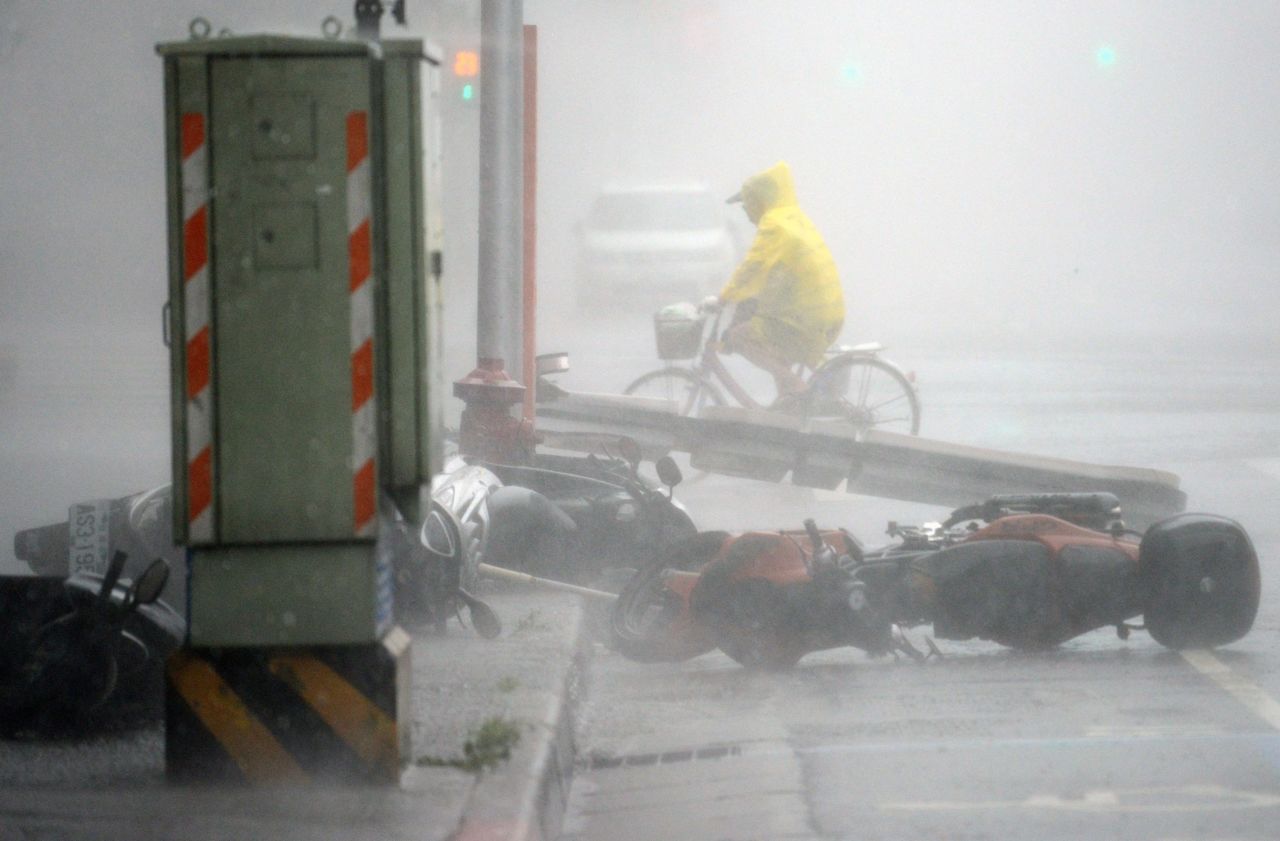 A man rides past blown-down motorcycles as Typhoon Soudelor hits Taipei on August 8.