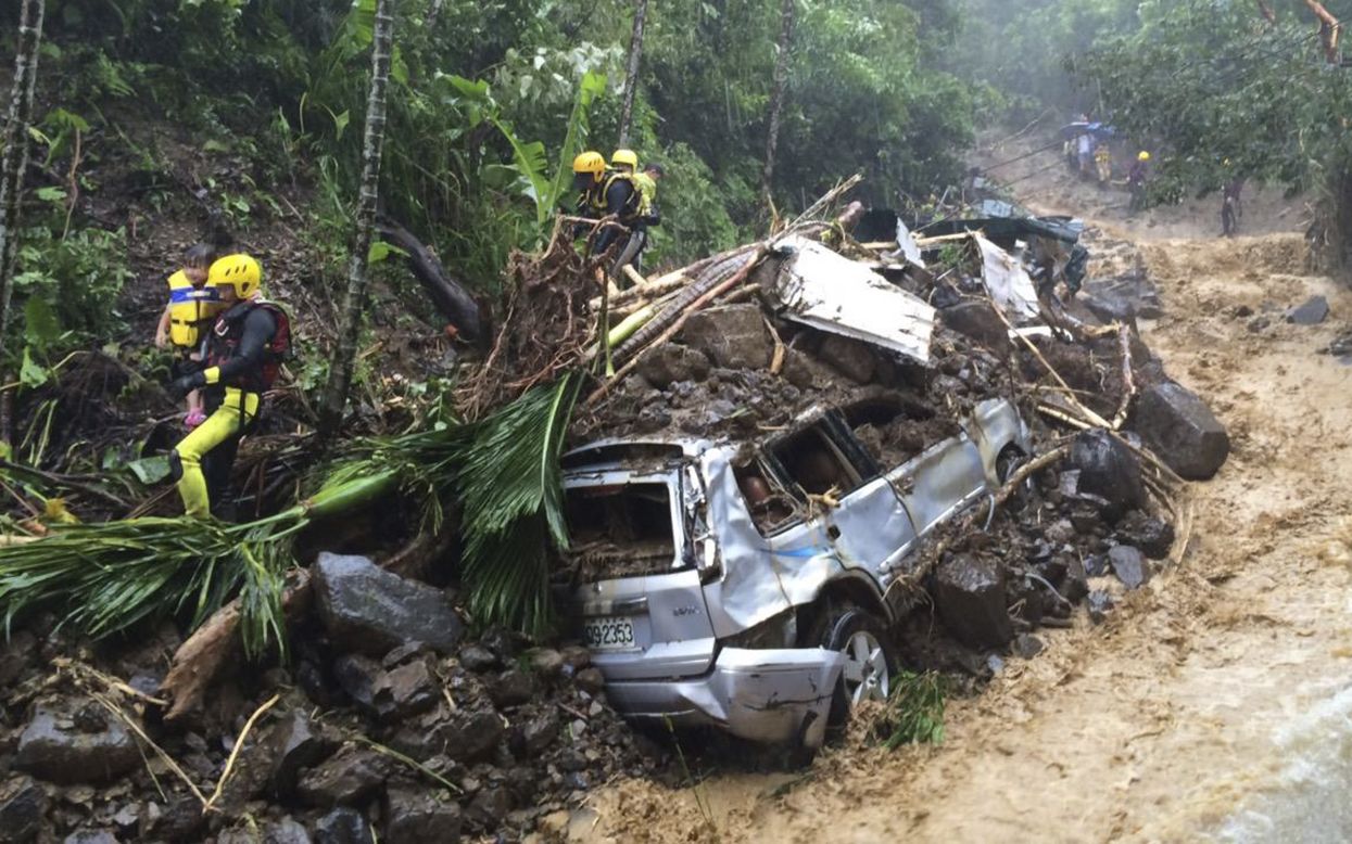 Emergency rescue personnel carry children past cars crushed by a mudslide in New Taipei City on August 8. 