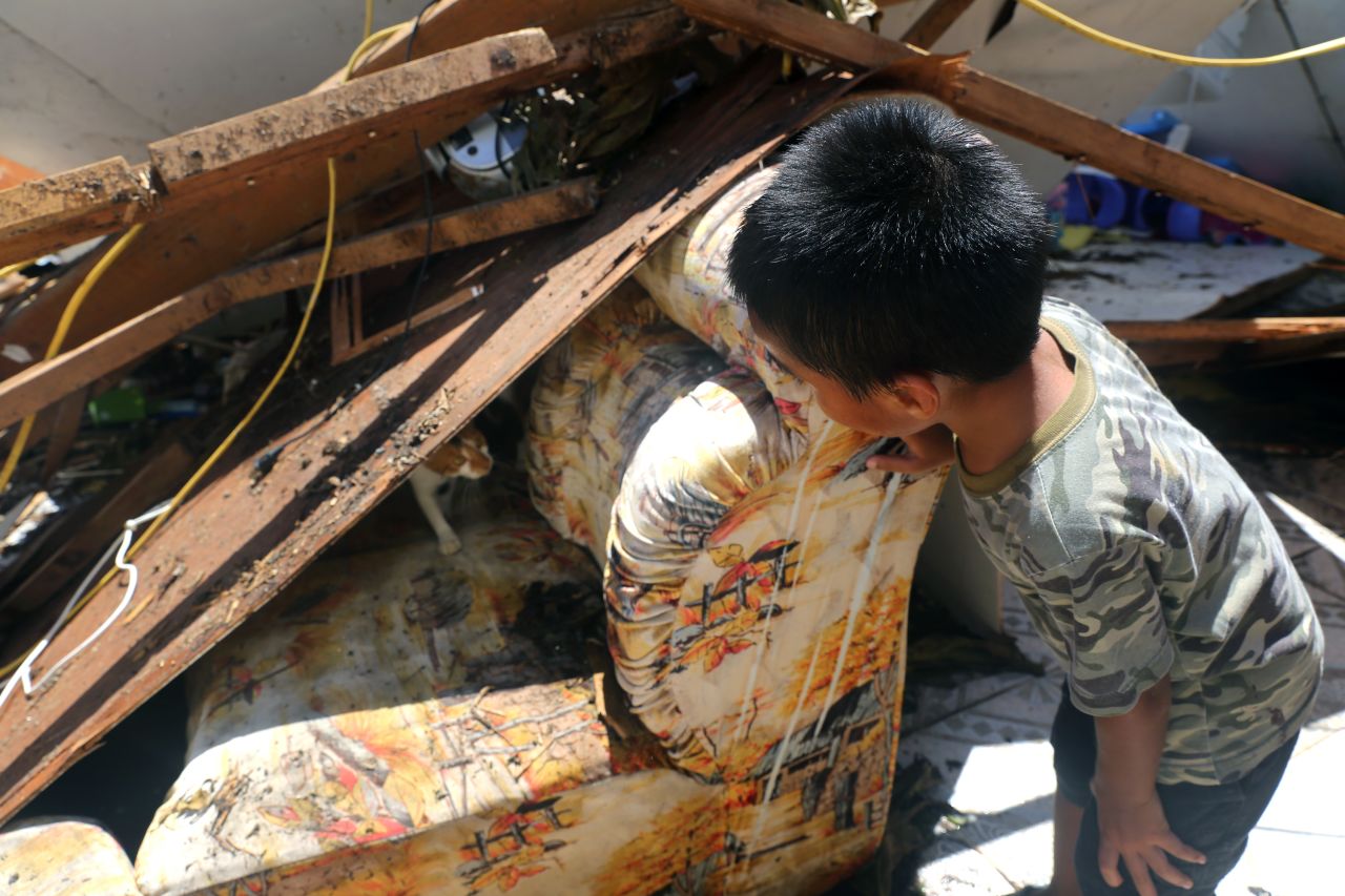 A young boy finds a mother cat nursing two kittens as he searches through the storm-damaged remains of his home on August 8 in Saipan, Northern Mariana Islands. 