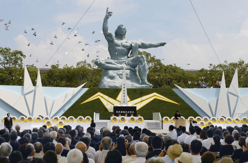 Doves fly over the Statue of Peace at Nagasaki Peace Park.