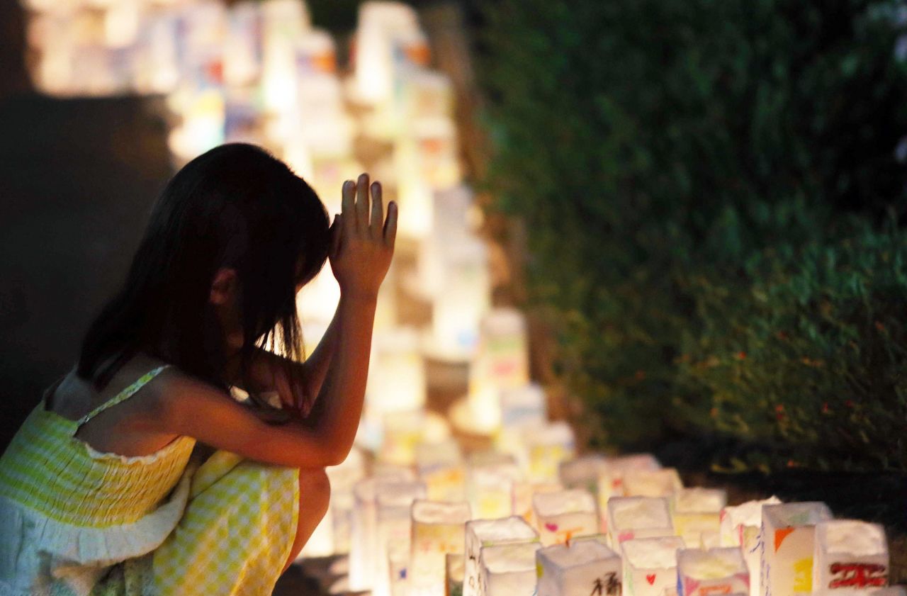 A girl offers a prayer to the victims before lanterns are placed at the Peace Memorial Park in Nagasaki on Saturday, August 8. 