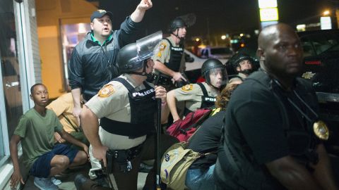 Police take cover as a barrage of gunfire erupts during a demonstration to mark the 1-year anniversary of the shooting of Michael Brown on August 9, 2015 in Ferguson, Missouri. Brown was shot and killed by a Ferguson police officer on August 9, 2014. His death sparked months of sometimes violent protests in Ferguson and drew nationwide focus on police treatment of black offenders. 