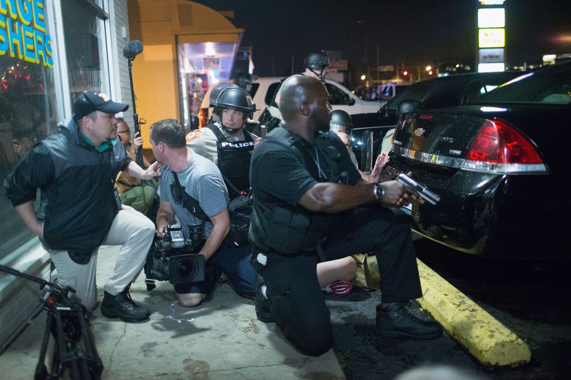 Police take cover as a barrage of gunfire erupts during a demonstration to mark the one-year anniversary of the shooting of Michael Brown on August 9, 2015, in Ferguson, Missouri. 