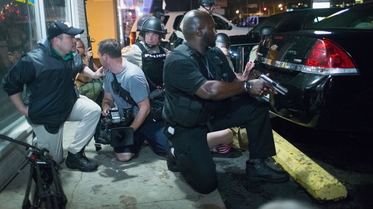 Police take cover as a barrage of gunfire erupts during a demonstration to mark the one-year anniversary of the shooting of Michael Brown on August 9, 2015, in Ferguson, Missouri. 