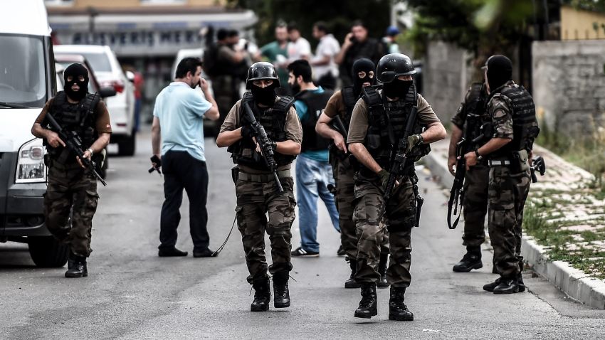 Turkish special force police officers take cover during clashes with attackers on August 10, 2015 at the Sultanbeyli district in Istanbul. Turkey's largest city Istanbul was Monday shaken by twin attacks on the US consulate and a police station as tensions spiral amid the government's air campaign against Kurdish militants.