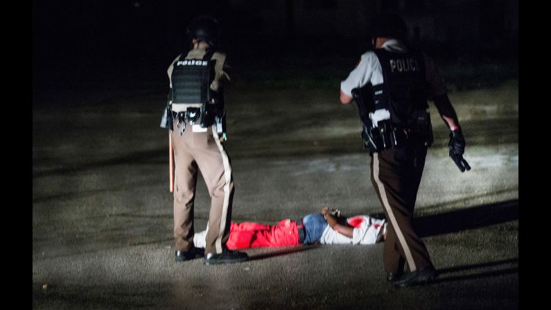 A man with gunshot wounds lies face down in a parking lot after a shootout with police in Ferguson on Sunday, August 9. Demonstrations started peacefully, but gunfire erupted Sunday night. Police say the man fired at them.