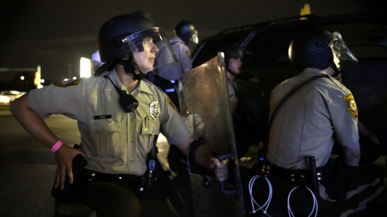 Police take cover after gunfire in Ferguson on August 9.