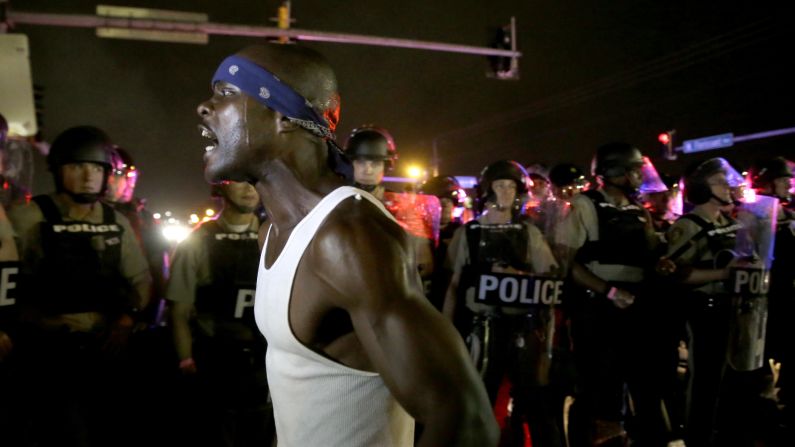A protester yells in front of a line of police in Ferguson on August 9.