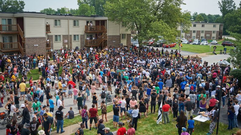 People attend a memorial service outside Canfield Apartments in Ferguson on August 9. Several hundred demonstrators stood in silence at the spot where Brown was shot and killed.