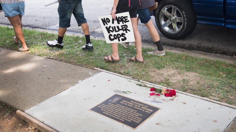 People walk past a plaque honoring Brown following the memorial service in Ferguson on August 9.