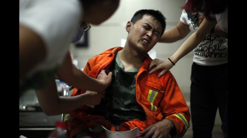 A firefighter grimaces as he is examined for injuries. Seventeen firefighters were among the people killed, officials said.