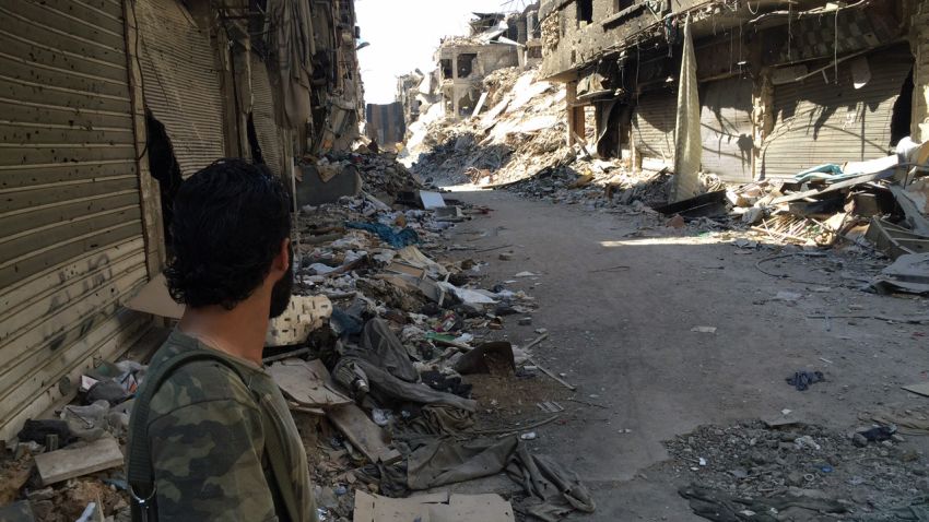A Palestinian pro-regime fighter surveys the devastated landscape of Yarmouk district in Damascus on August 12, 2015.