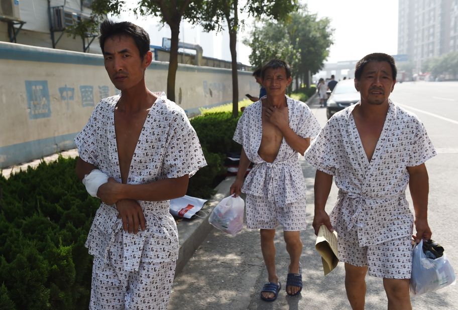 Three men walk out onto the streets after being treated at a hospital on Thursday, August 13.