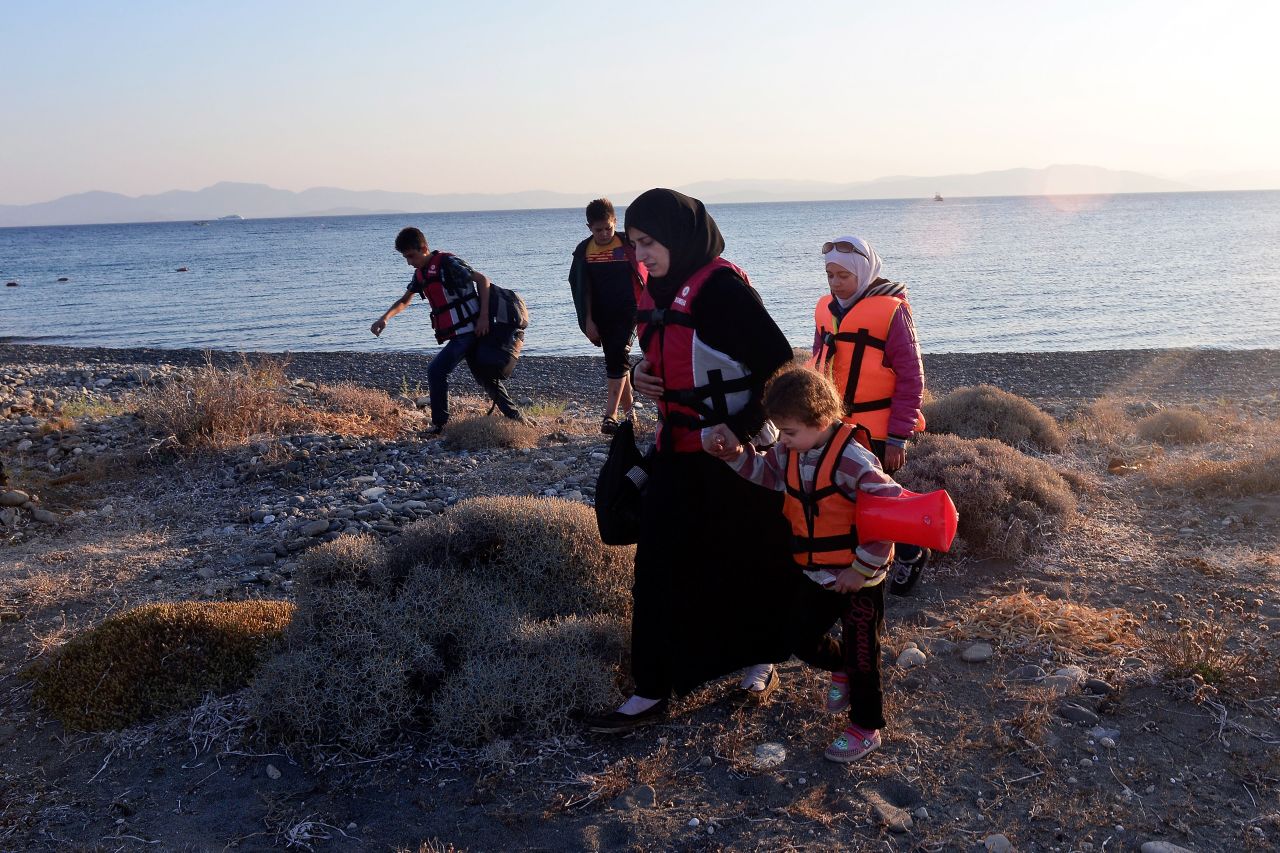 A Syrian migrant mother holds the hand of a child as they arrive at a beach on Kos on August 13. 