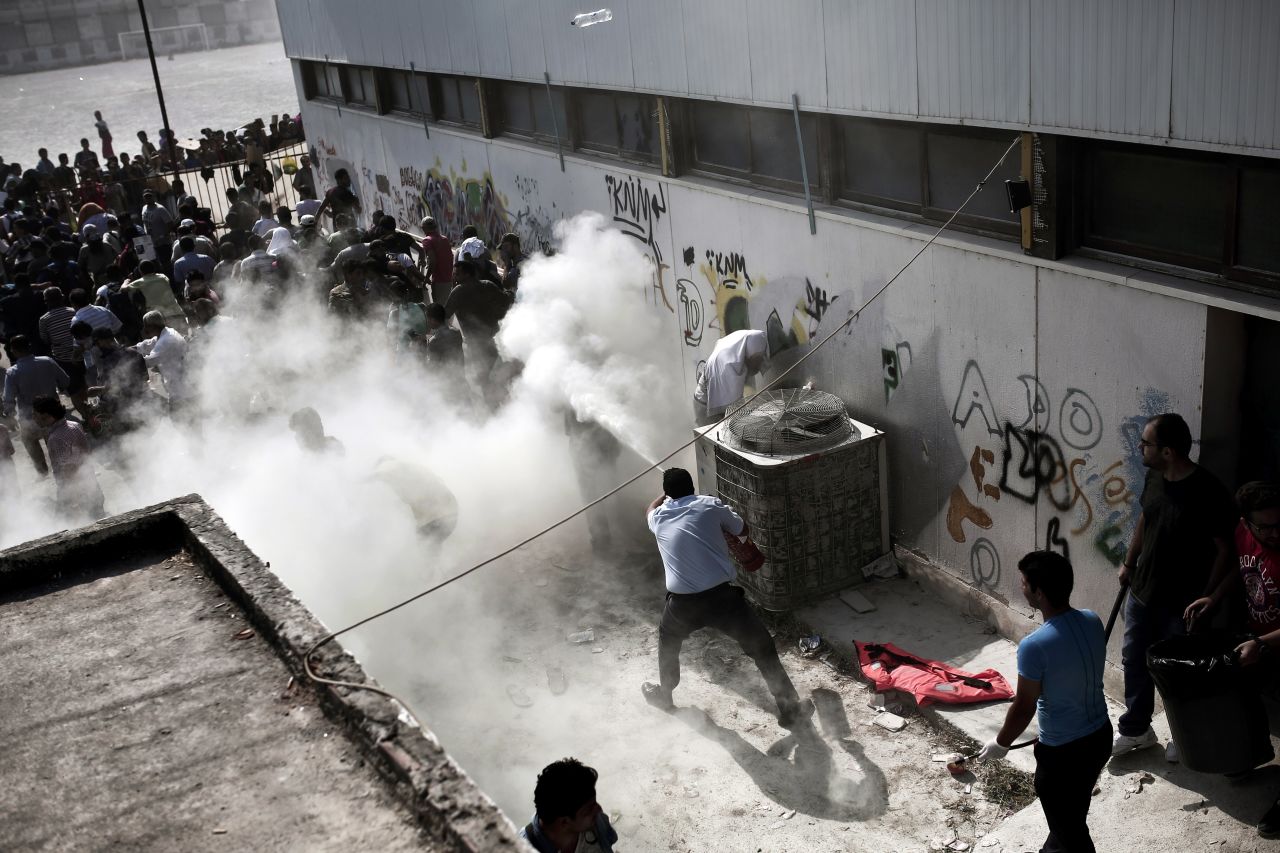 Policemen try to disperse hundreds of migrants by spraying them with fire extinguishers during a gathering for a registration procedure at a stadium on the Greek island of Kos, on Tuesday, August 11.  The migrants had been ordered to go to the stadium by police who carried out a sweep of parks and public squares where they'd congregated. With no shade, toilets or water provided, the situation deteriorated.