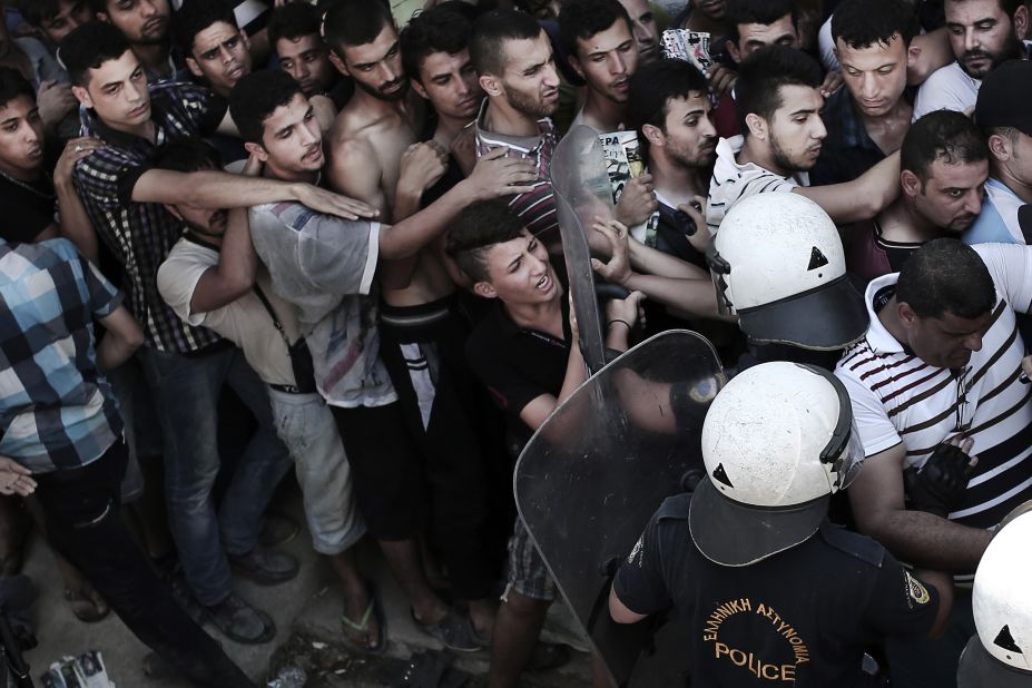 A policeman pushes a man as hundreds wait to complete registration at a stadium in Kos on August 12.