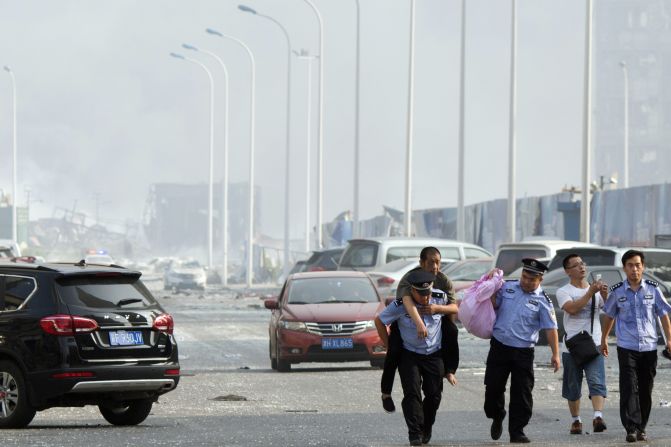 A Chinese police officer carries a man as civilians flee the area near the disaster.