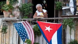 A Cuban gives the thumbs up from his balcony decorated with the US and Cuban flags in Havana, on January 16, 2015. The United States will ease travel and trade restrictions with Cuba on Friday, marking the first concrete steps towards restoring normal ties with the Cold War-era foe since announcing a historic rapprochement. AFP PHOTO/YAMIL Lage        (Photo credit should read YAMIL LAGE/AFP/Getty Images)