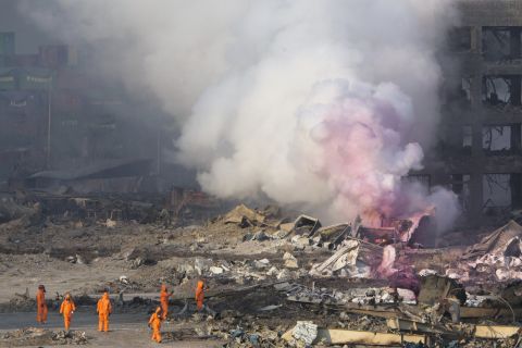 Firefighters wear protective gear while working as partially pink smoke billows nearby. The environmental group Greenpeace expressed concern "that certain chemicals will continue to pose a risk to the residents of Tianjin," and city residents shared similar fears on social media.  