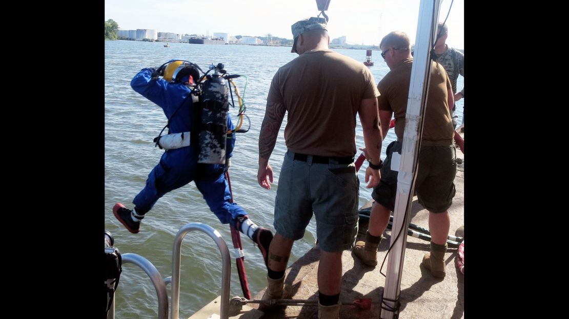 A U.S. Navy diver, after a briefing and gear check, strides into the turbid Savannah River.