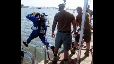 A U.S. Navy diver, after a briefing and gear check, strides into the turbid Savannah River.