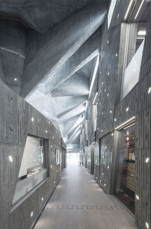 The Niigata City Konan Ward Cultural Center's simple, bunker-like exterior is juxtaposed with a playful interior. The walls are dotted with seemingly random slits that either allow in natural light from outdoors or hold florescent bulbs.