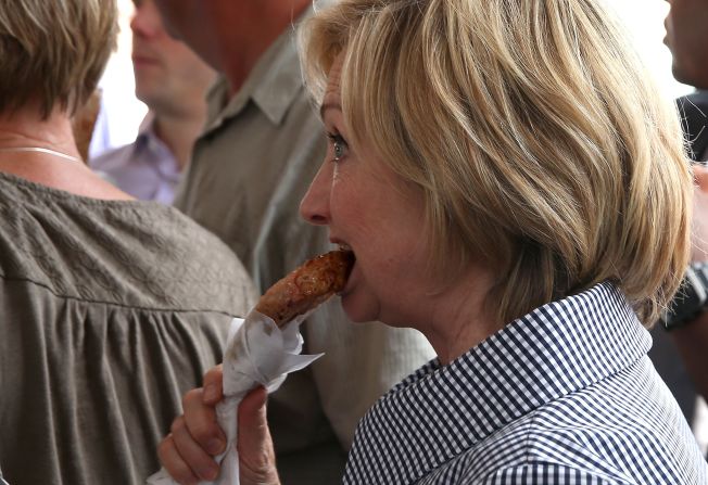 Clinton eats a pork chop on a stick as she tours the fair on August 15.