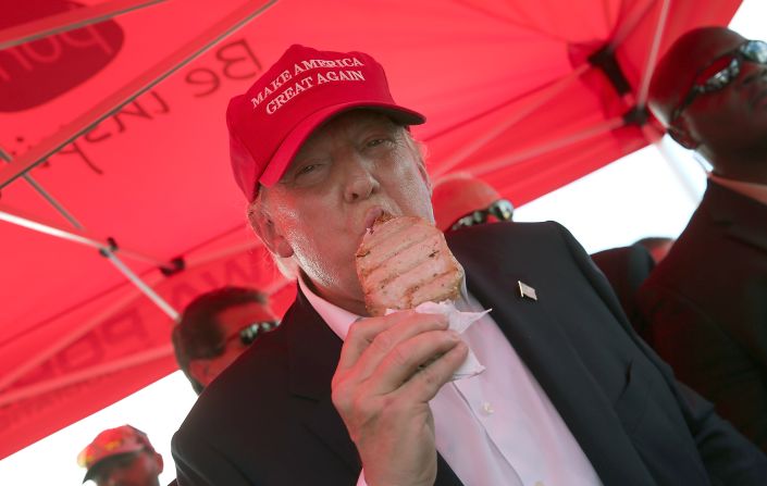 Trump eats a pork chop on a stick while attending the fair on August 15.