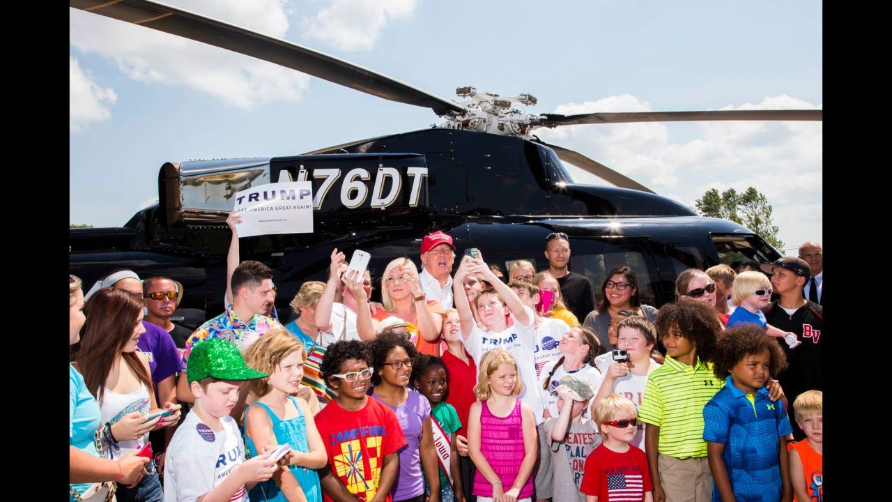Trump poses with supporters' children before taking some of them on a free helicopter ride. He arrived at the fair shortly after 1 p.m. in grand fashion, landing in his private helicopter with "TRUMP" emblazoned on its side. The fair wouldn't let Trump's helicopter take off from the fairgrounds, so he used a nearby parking lot to make the flights.