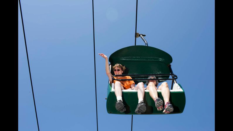 A woman riding a chairlift waves at Bush. 