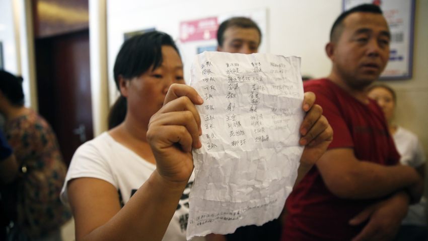 A woman (C) holds a name list of missing firefighters as family members talk to media to seek for help after being barred from a press conference authorities have at a hotel in Tianjin on August 15, 2015. Furious, frustrated and fearful, relatives of the missing in giant explosions in Tianjin besieged officials on August 15 demanding answers on their loved ones's fates- only for security to intervene instead.CHINA OUT     AFP PHOTO        (Photo credit should read STR/AFP/Getty Images)