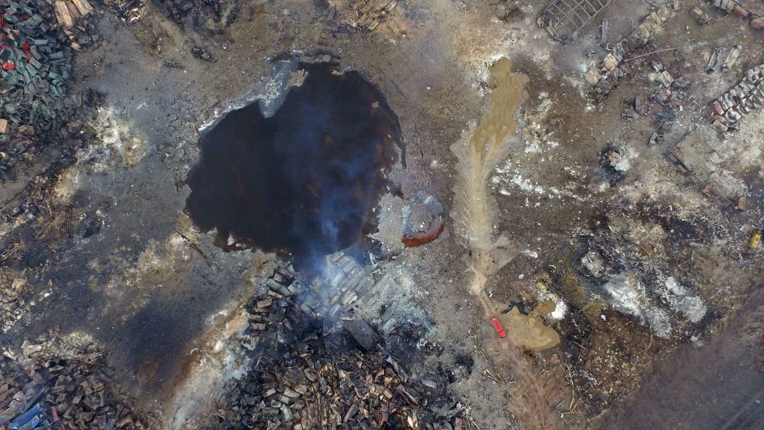 Smoke rises from debris on Saturday, August 15, near a crater that was at the center of a series of explosions in northeastern China's Tianjin municipality as seen from an aerial view.