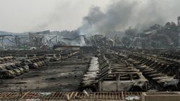 Smoke continues to billow from behind rows of burnt out Volkswagen cars the second morning after a series of explosions at a chemical warehouse hit the city of Tianjin, in northern China on August 14, 2015.  A Chinese military team of nuclear and chemical experts began work on August 14 at the site of two massive explosions in the city of Tianjin, state media said, as pressure grows for authorities to explain the cause of blasts that left 50 dead.    AFP PHOTO / FRED DUFOUR        (Photo credit should read FRED DUFOUR/AFP/Getty Images)